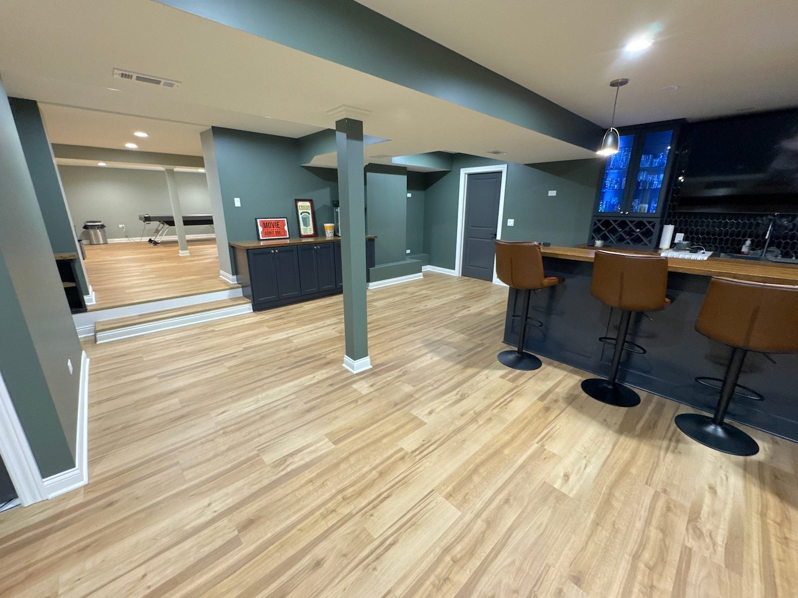 Gold basement: wet bar with butcher-block top, lit glass cabinets and bar seating