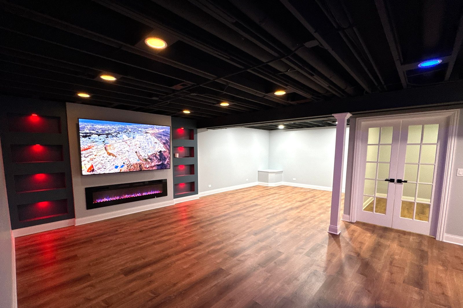 Basement media wall with LED-lit niches and black ceiling
