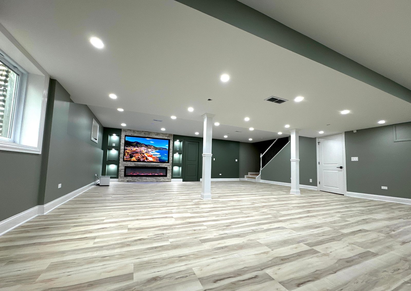 Open basement with media wall, fireplace and wood-look flooring
