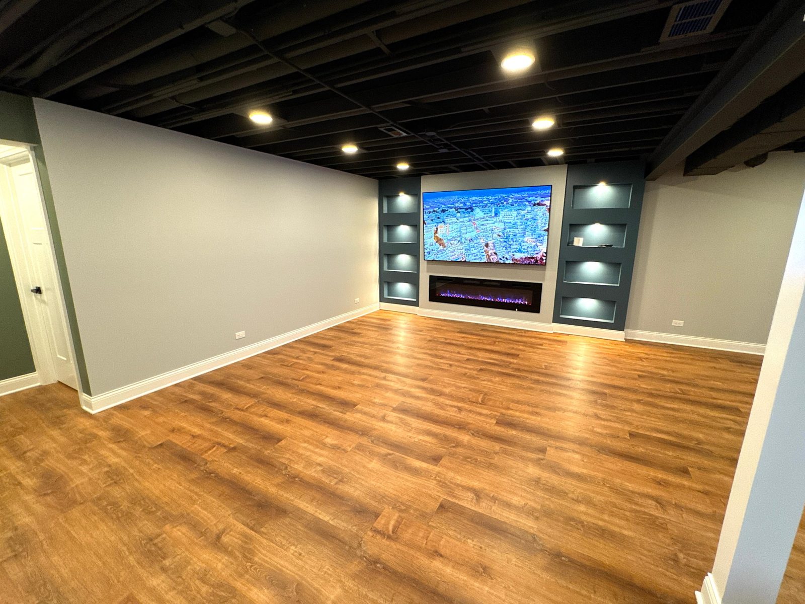 Silver basement: open room with built-in media wall, electric fireplace and lit niches
