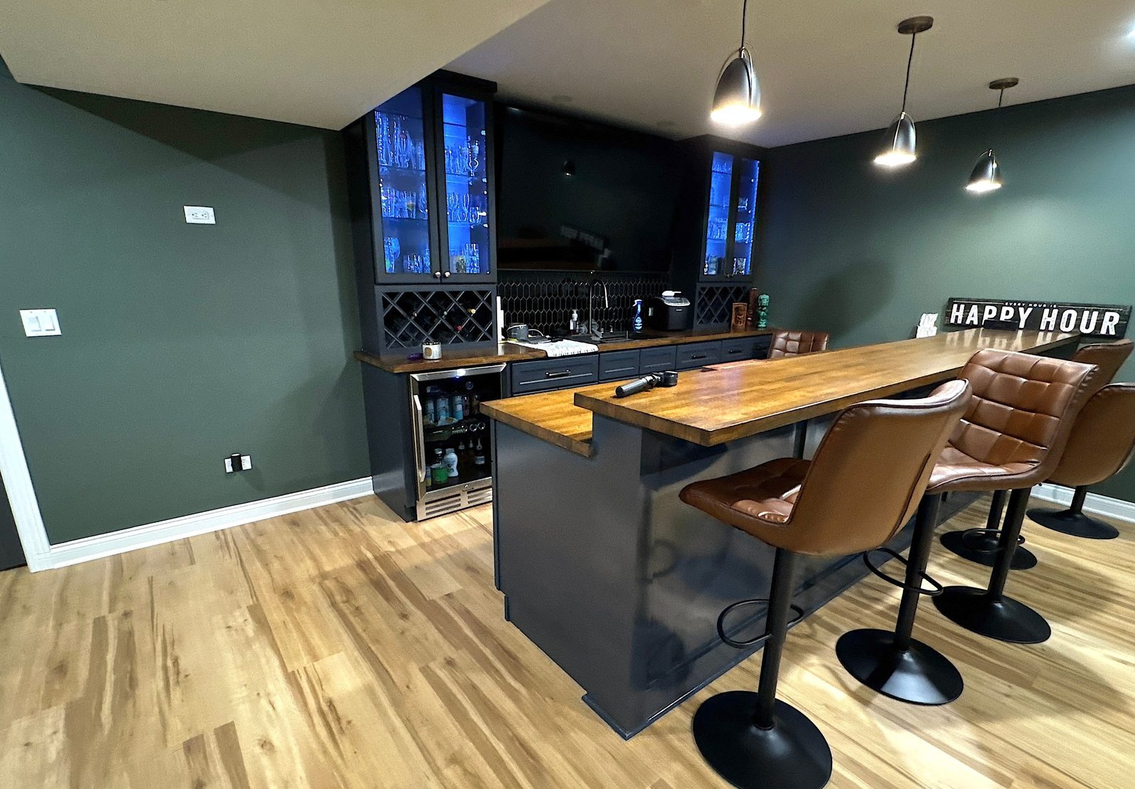 Basement wet bar with butcher block top and lit glass cabinets