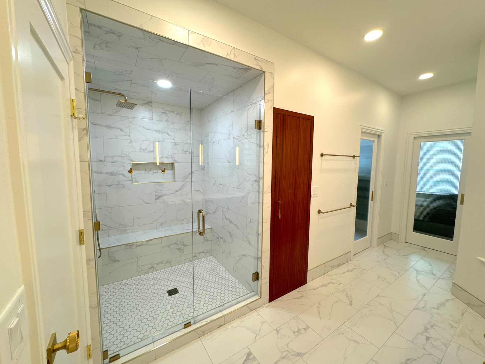 Gold bathroom: walk-in marble-look shower with bench, rain head and frameless glass