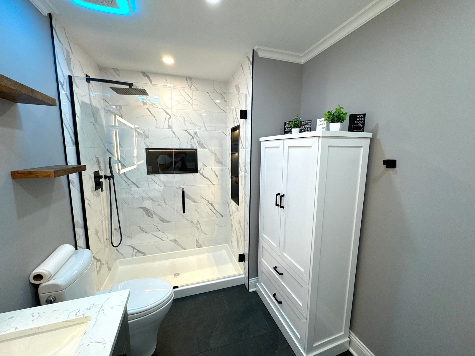 Silver bathroom: marble-look tiled shower with black fixtures and lit niche, rebuilt to the studs