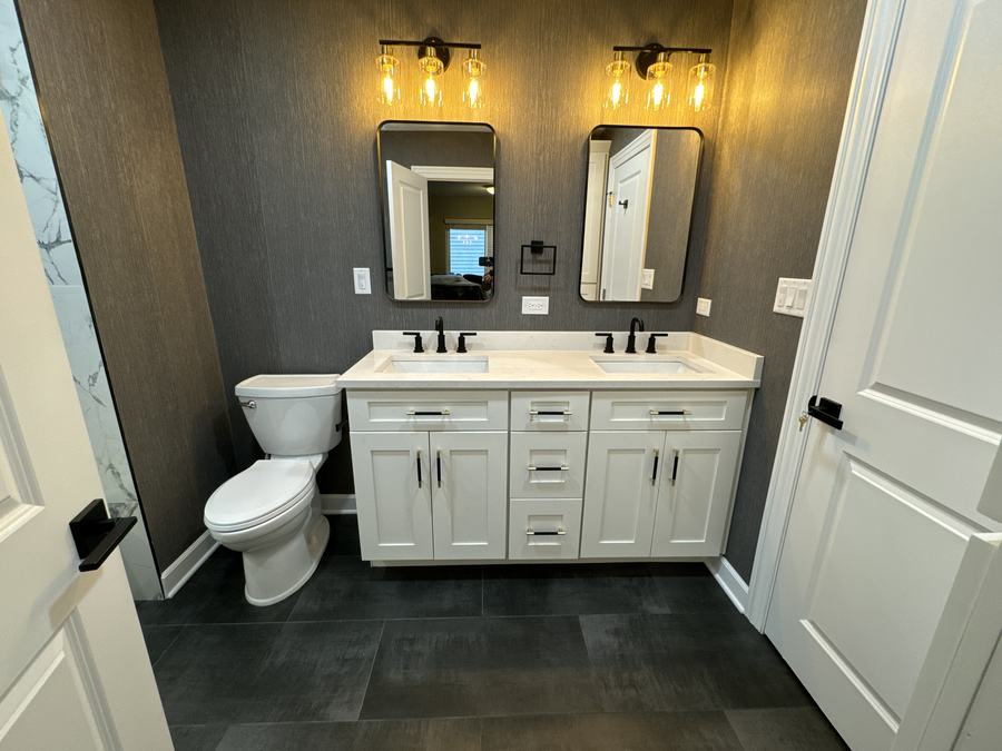 Bathroom with double vanity and dark tile floor