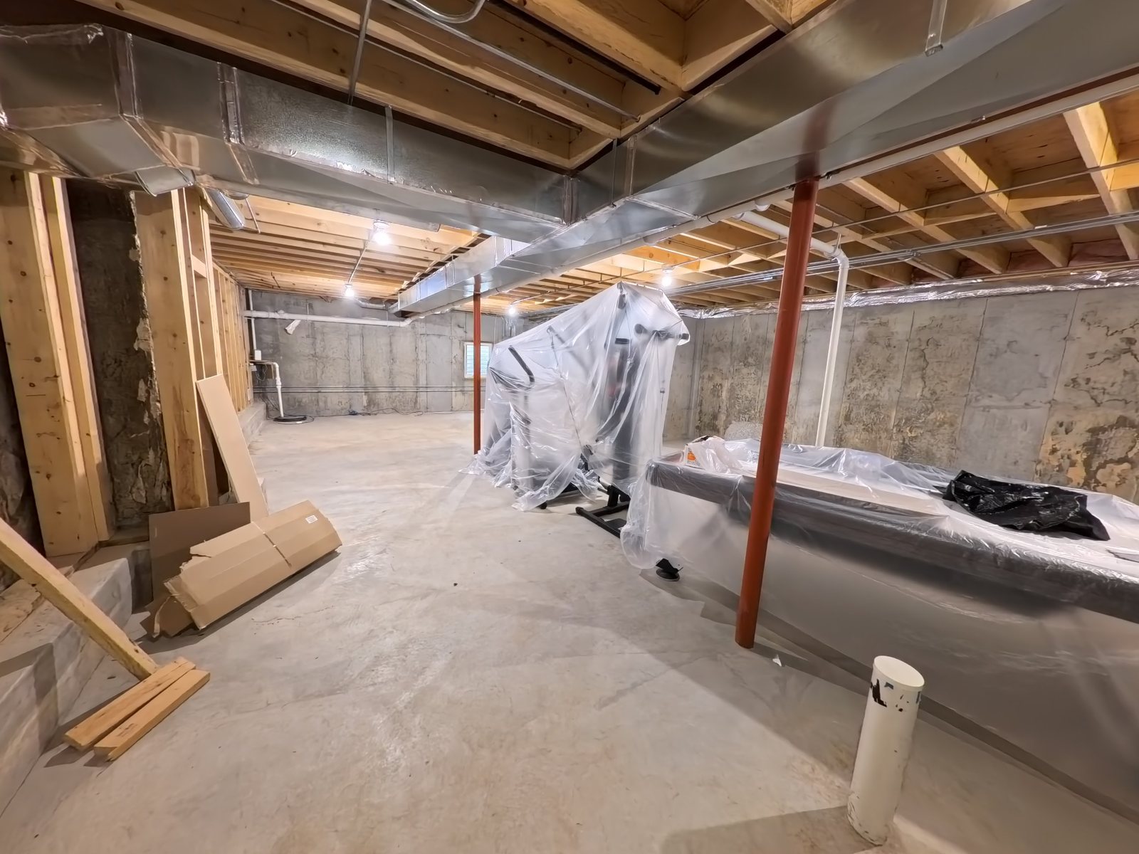 Basement before the remodel: bare concrete walls and open ductwork
