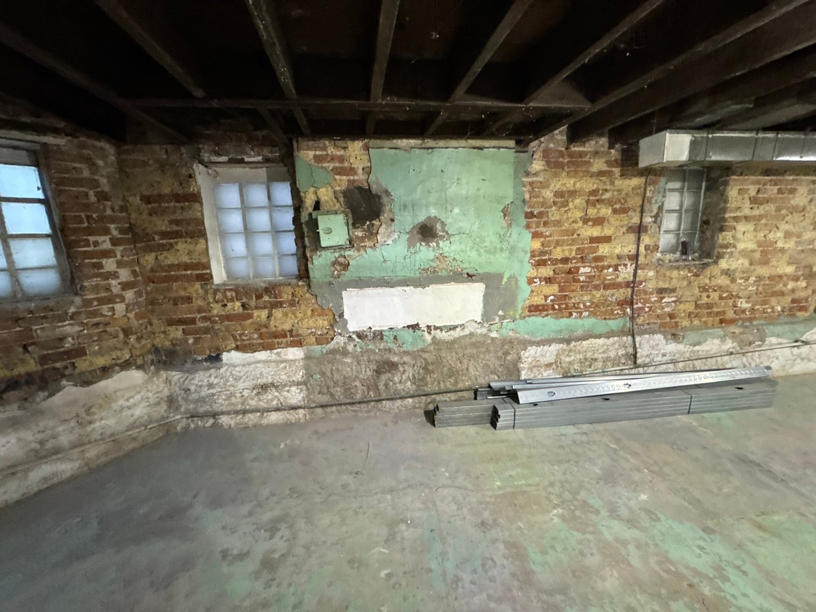 Basement before the remodel: old brick walls and bare concrete floor