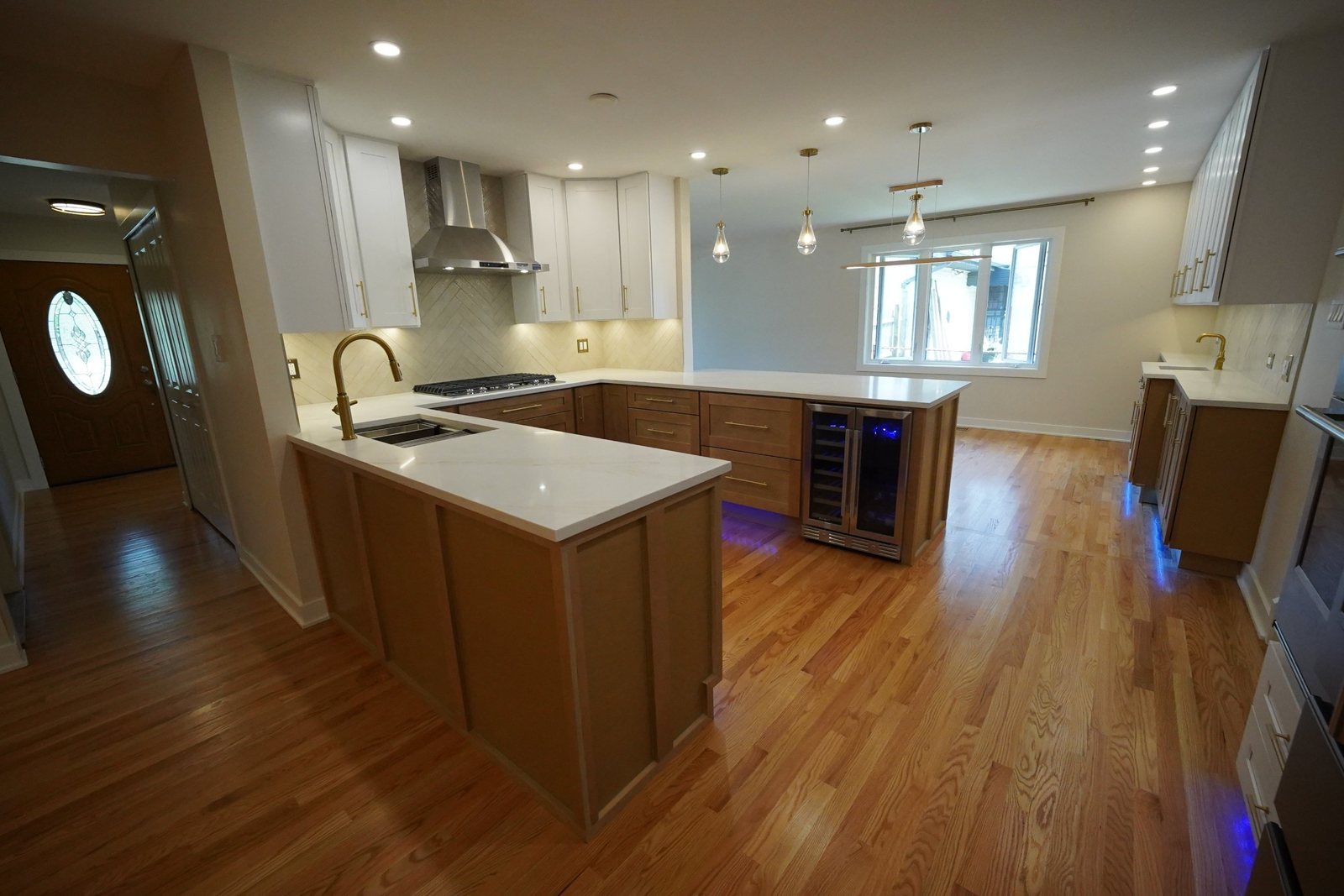 Finished kitchen with white and wood cabinets, quartz counters and gold fixtures