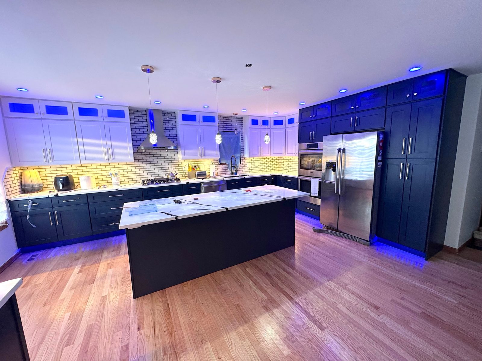 Finished kitchen with navy and white cabinets and LED lighting