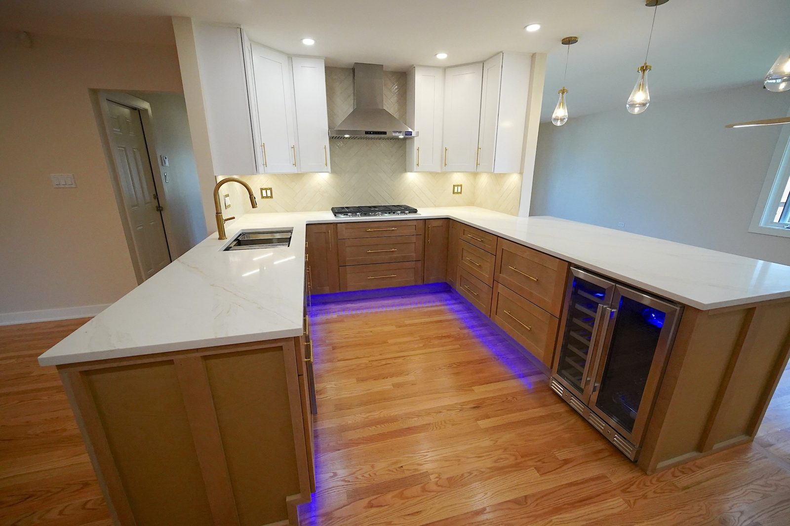 Silver kitchen: U-shaped layout with white uppers, wood base cabinets, quartz peninsula and wine fridge