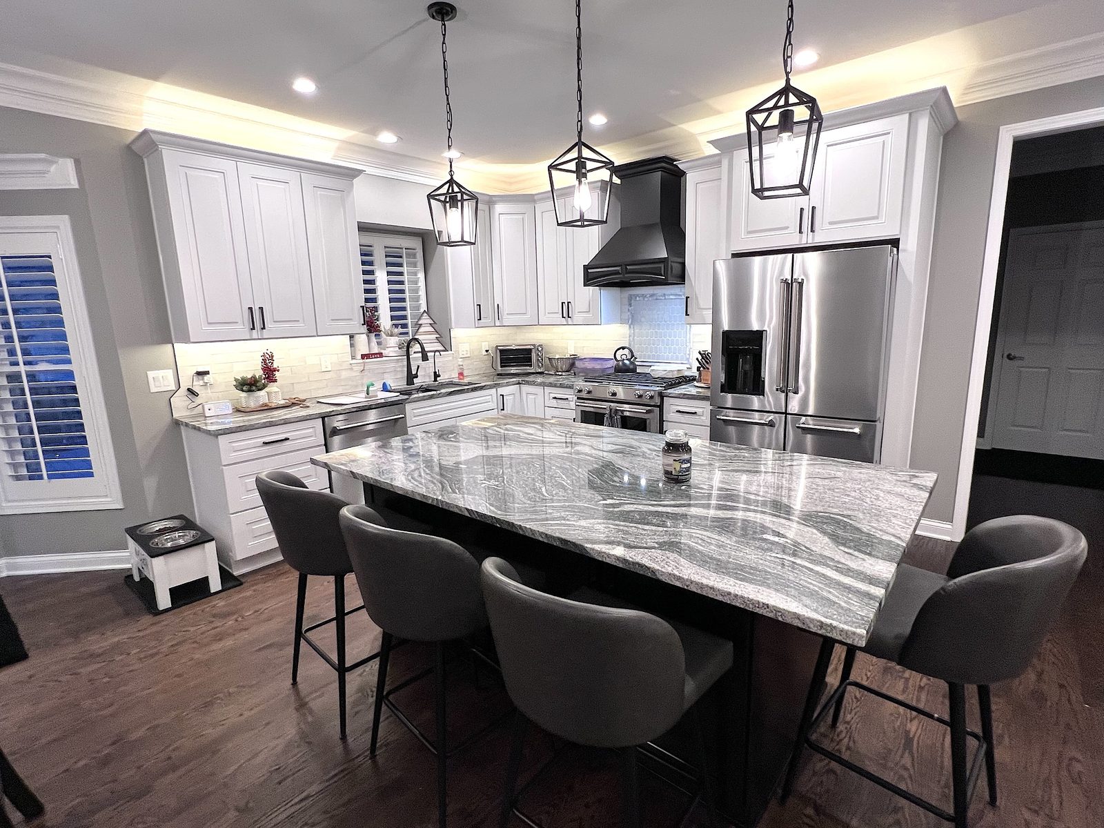 White kitchen with granite island and black range hood
