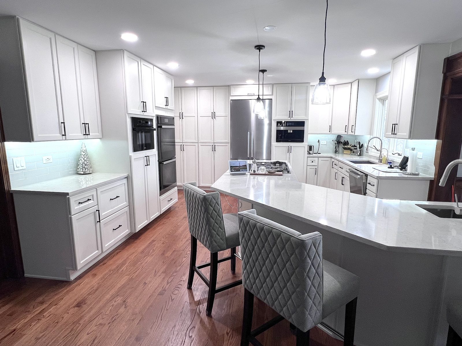 White kitchen with quartz peninsula and built-in ovens
