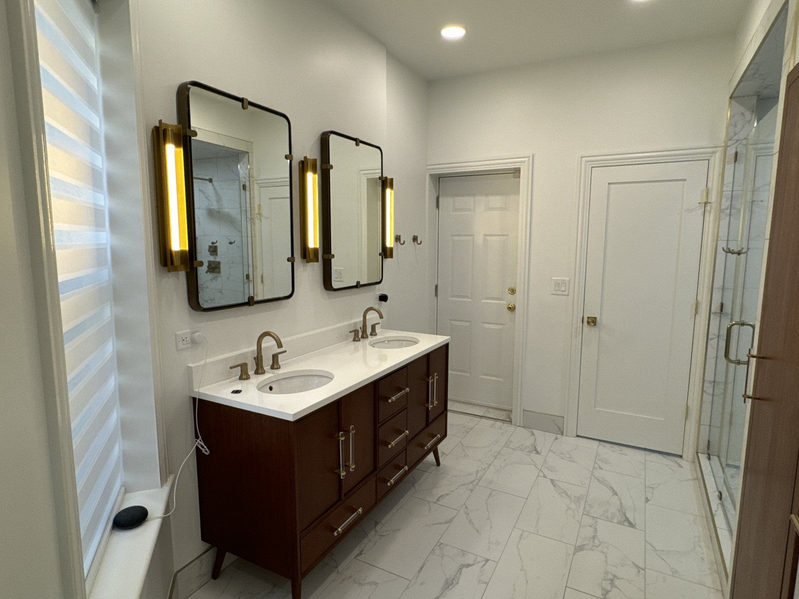 Walnut double vanity with brass hardware and framed mirrors with sconces