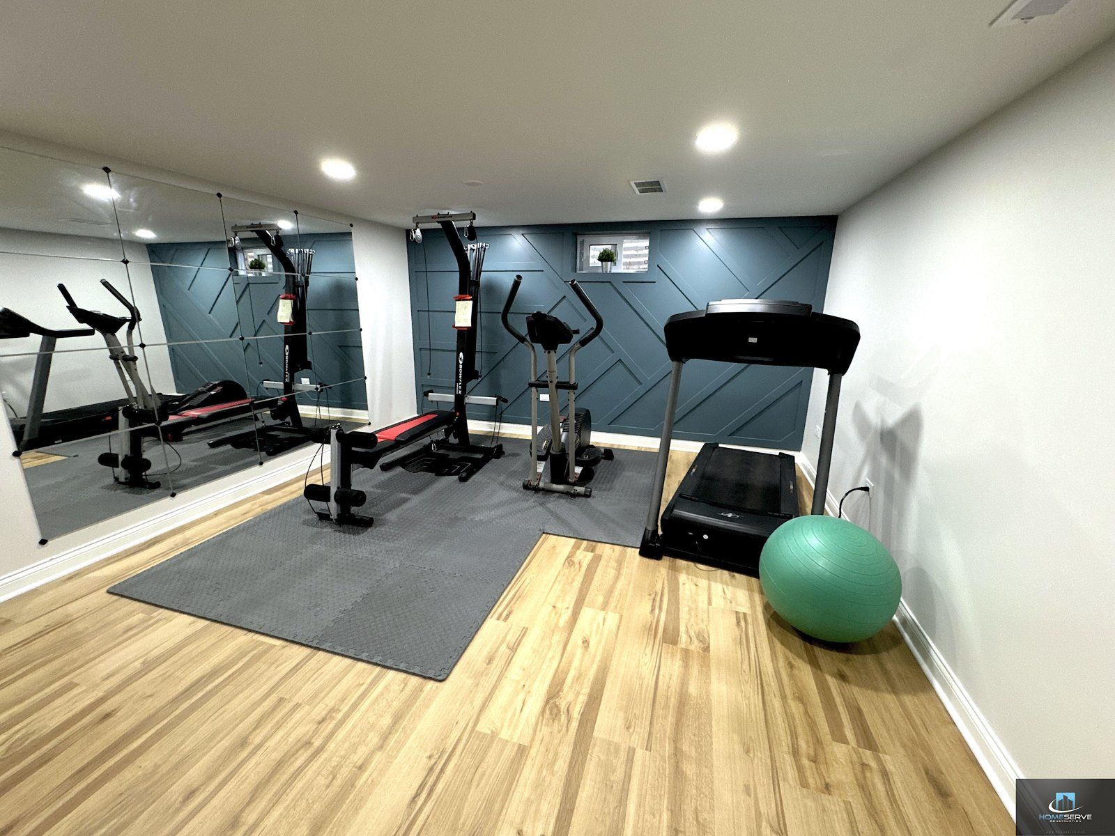 Finished basement home gym with equipment and accent wall