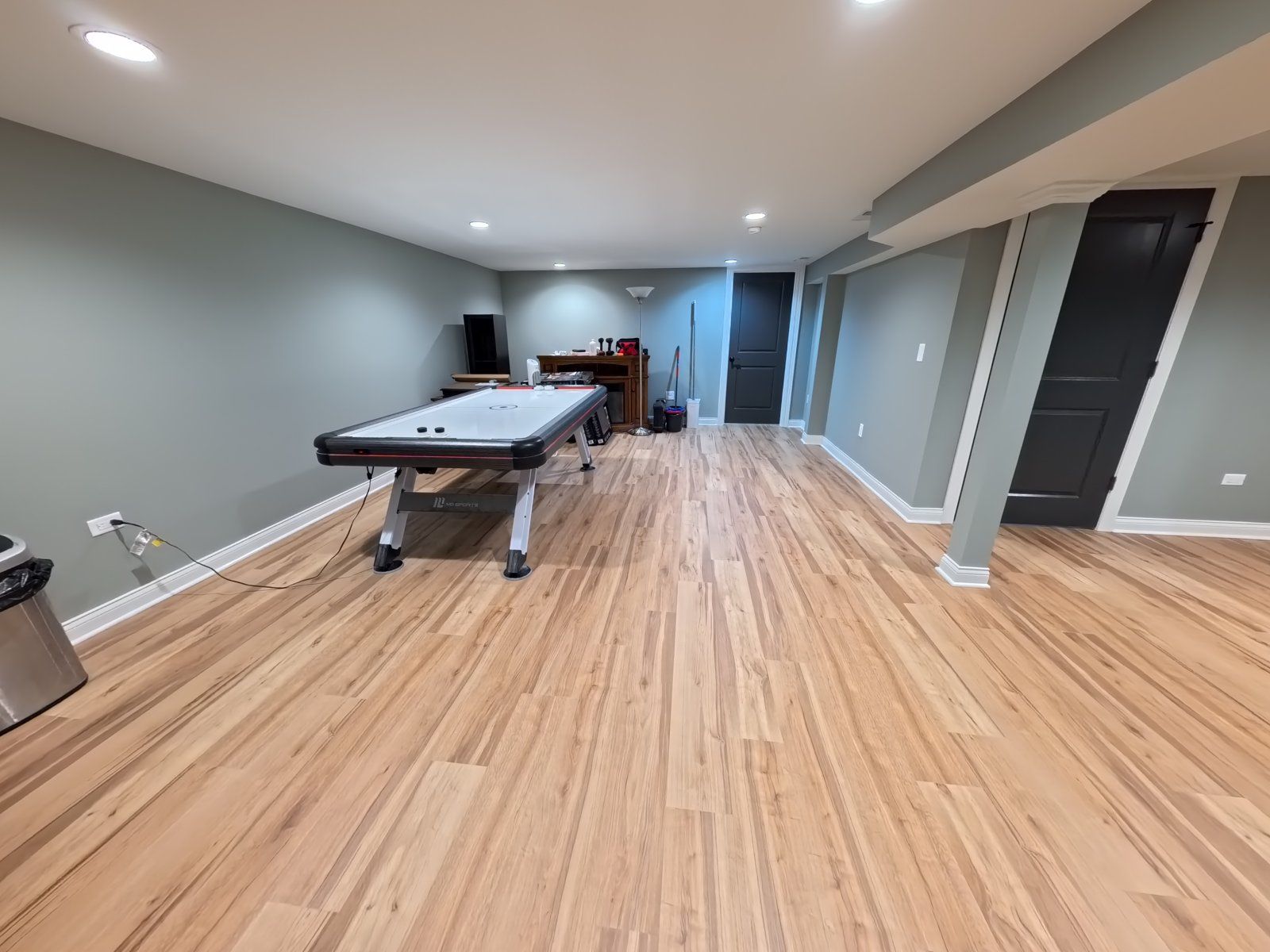 Open finished basement with an air hockey table and wood flooring